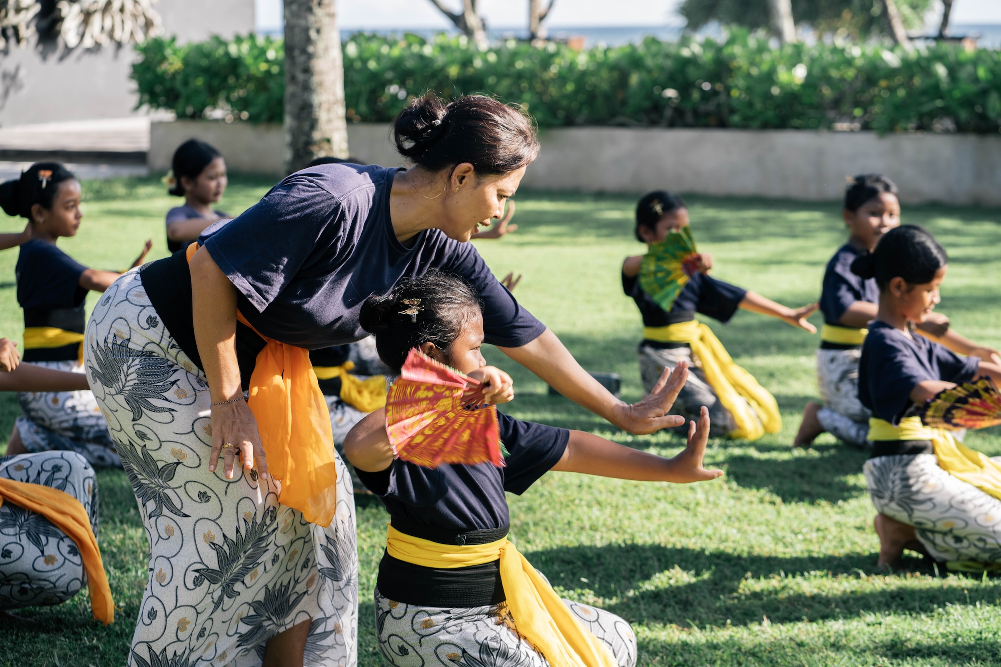 Balinese dance teacher guiding children during an outdoor rehearsal
